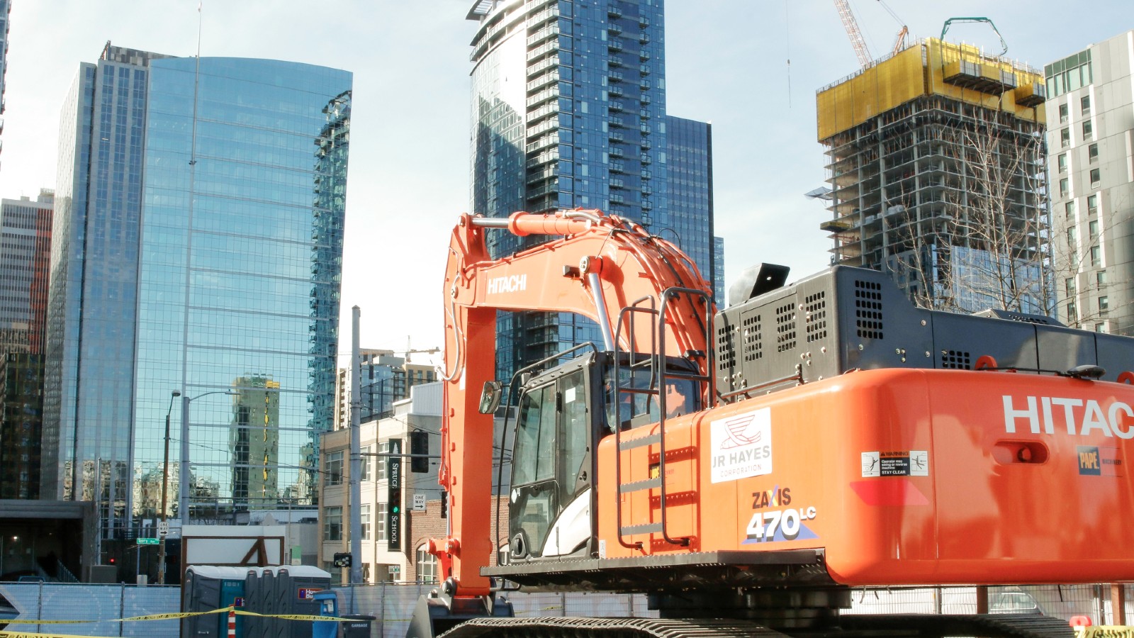 a backhoe at a construction site with large buildings around it