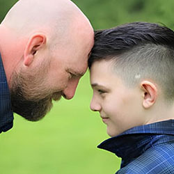 Thomas Gordon and his son facing each other and touching foreheads 