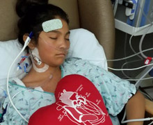 Shanae in hospital bed with heart pillow