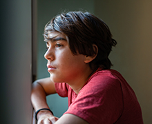 Teen boy looks longingly out a window