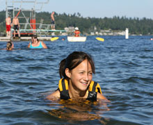 Teen swimming in water with life jacket on
