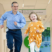 A man and a girl run down a hallway at Seattle Children's