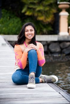 a girls smiles as she sits on a dock