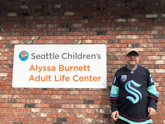 A man standing in front of the Alyssa Burnett Adult Life Center sign