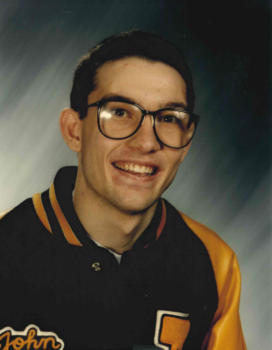 A teen boy smiles at the camera wearing his letterman jacket