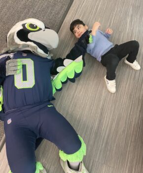 Blitz lays on the ground next to a young boy