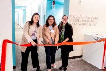 A ribbon cutting ceremony with three woman smiling at the camera