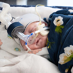 Sleeping baby in blanket wearing a mask