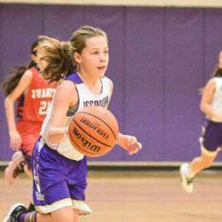 a girl dribbling a basketball in a game