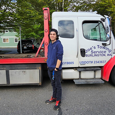 A man standing in front of a towing service truck
