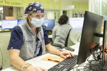 A nurse looks at a computer screen