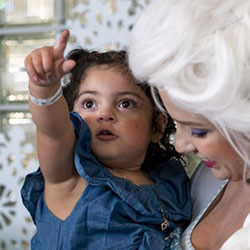A little girl points while in the arms of a princess in a Frozen costume