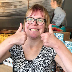 a young woman holds two thumbs up while smiling