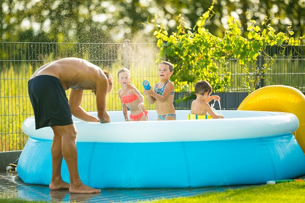 Kids playing in a back-yard pool with adult supervision