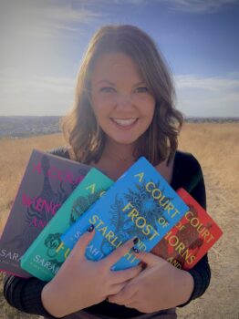 A young adult woman holds up four books