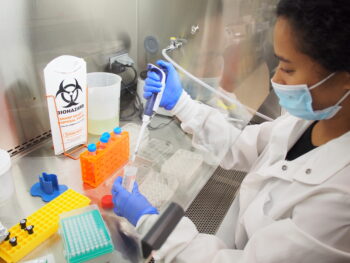 A summer scholars student conducts experiments at the lab bench