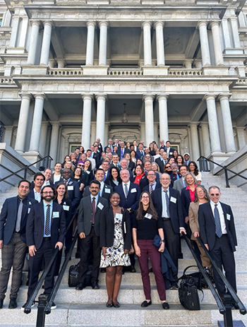 A group of cancer researchers pose together on the steps of Congress