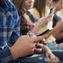 a group of teens all looking at their cell phones