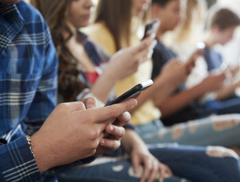 a group of teens all looking at their cell phones