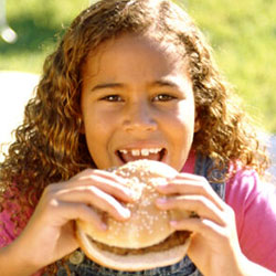 A girl eats a hamburger at a cookout