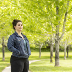 A young woman stands in a park