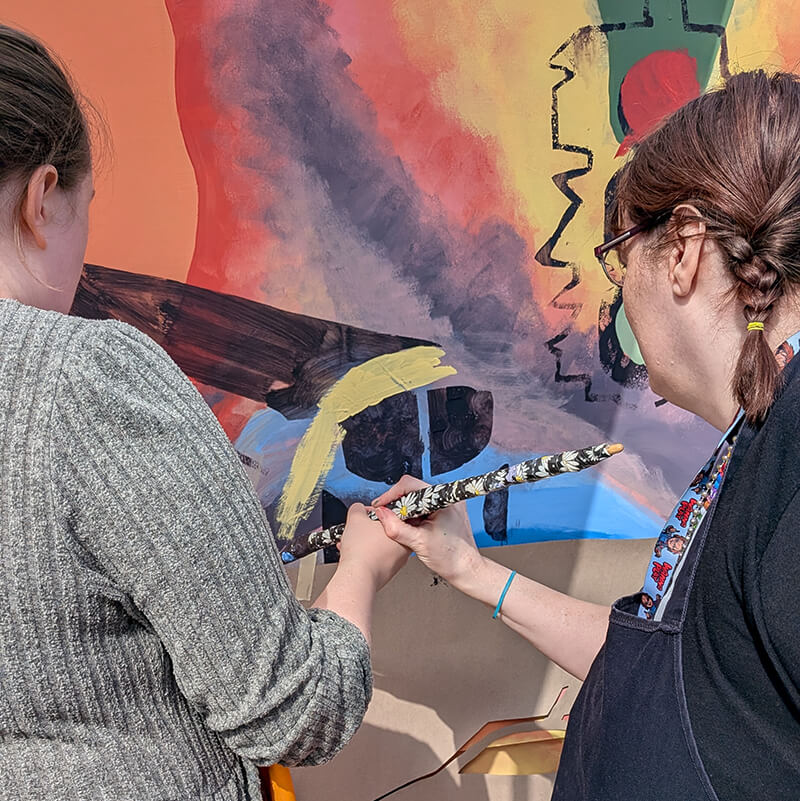 Two class participants painting a section of the mural
