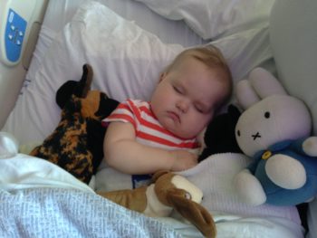 little girl sleeping with stuffies while in her hospital bed