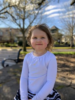 little girl smiling at the camera while in a park