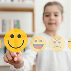 A child chooses their mood by pointing at an emoji.