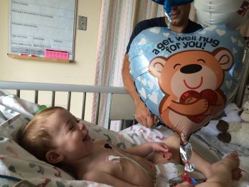 a toddler smiles in his hospital bed