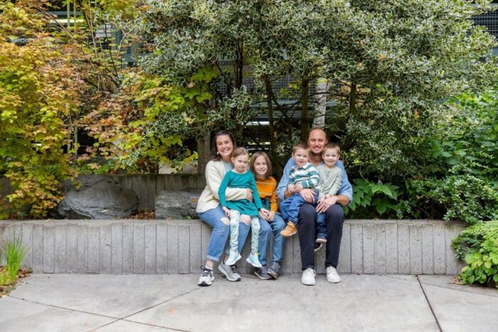 The Hatch family sits on a wall near a garden outside Seattle Children's Hospital
