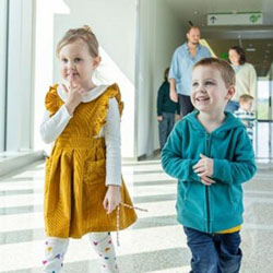 A brother and sister stand in a hallway with mom and dad in the background