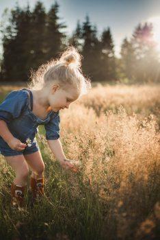 A little girl picks flowers in a field
