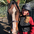 A girl stands next to her horse