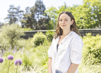 A woman smiles while standing in a garden