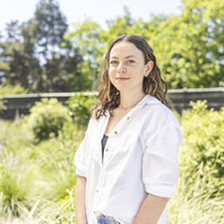 A woman smiles while standing in a garden