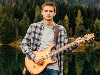 A teen boy holding a guitar