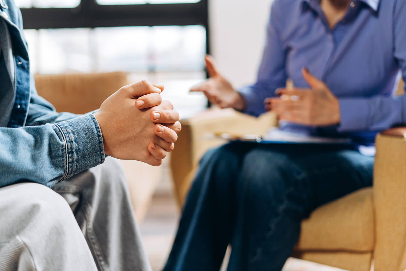 Close-up of a person's folded hands during a supportive counseling session.