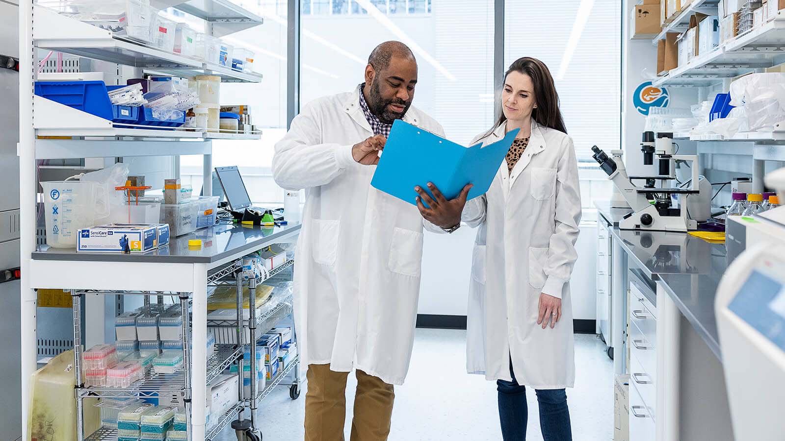 Dr. Evans and Dr. Pattwell in lab coats looking at a file