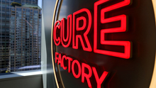Red neon sign reading 'Cure Factory'