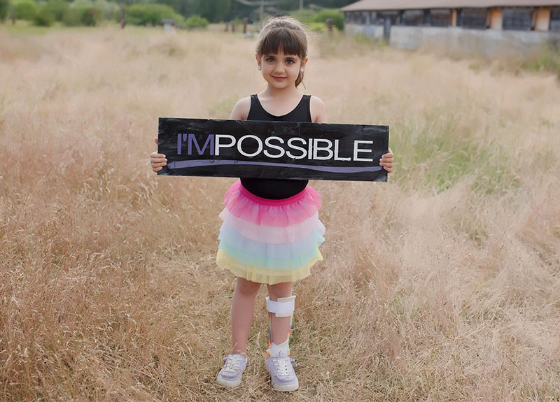 A girl holding a sign that says I'MPOSSIBLE