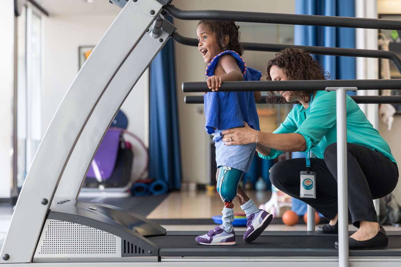 A girl learns to use her prosthetic on a treadmill