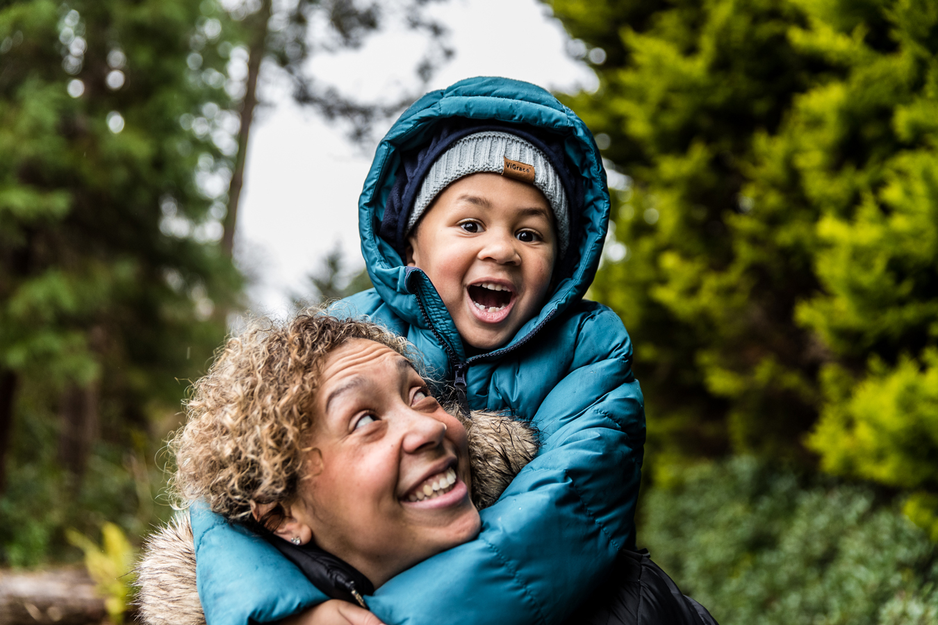 Isaac in blue puffy jacket riding on his mother's shoulders