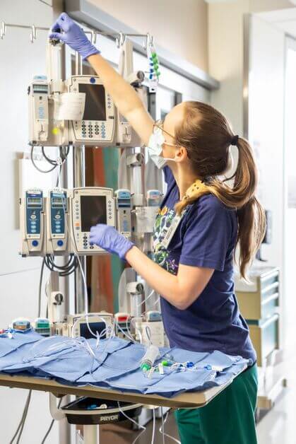 A female CICU nurse making adjustments to an IV pole