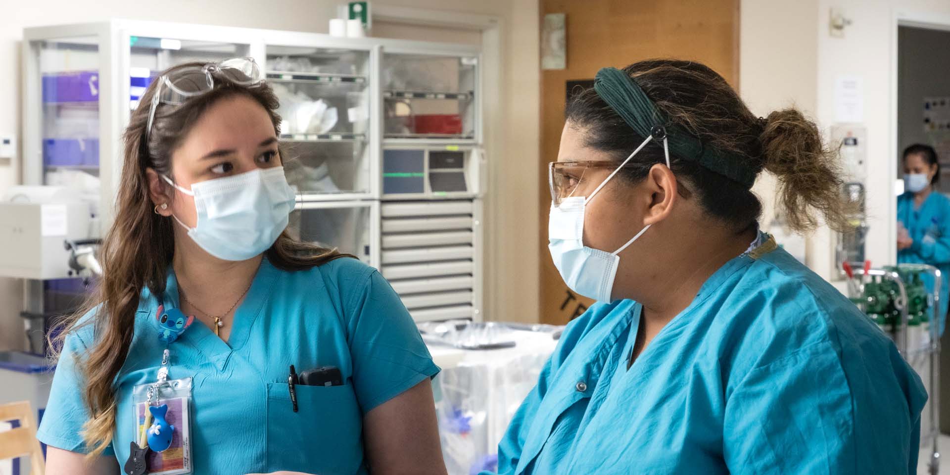 Two nurses in blue scrubs and surgical masks
