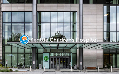 An exterior photo of an entrance to Seattle Children's Hospital with a branded sign above the awning