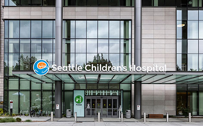 An exterior photo of an entrance to Seattle Children's Hospital with a branded sign above the awning
