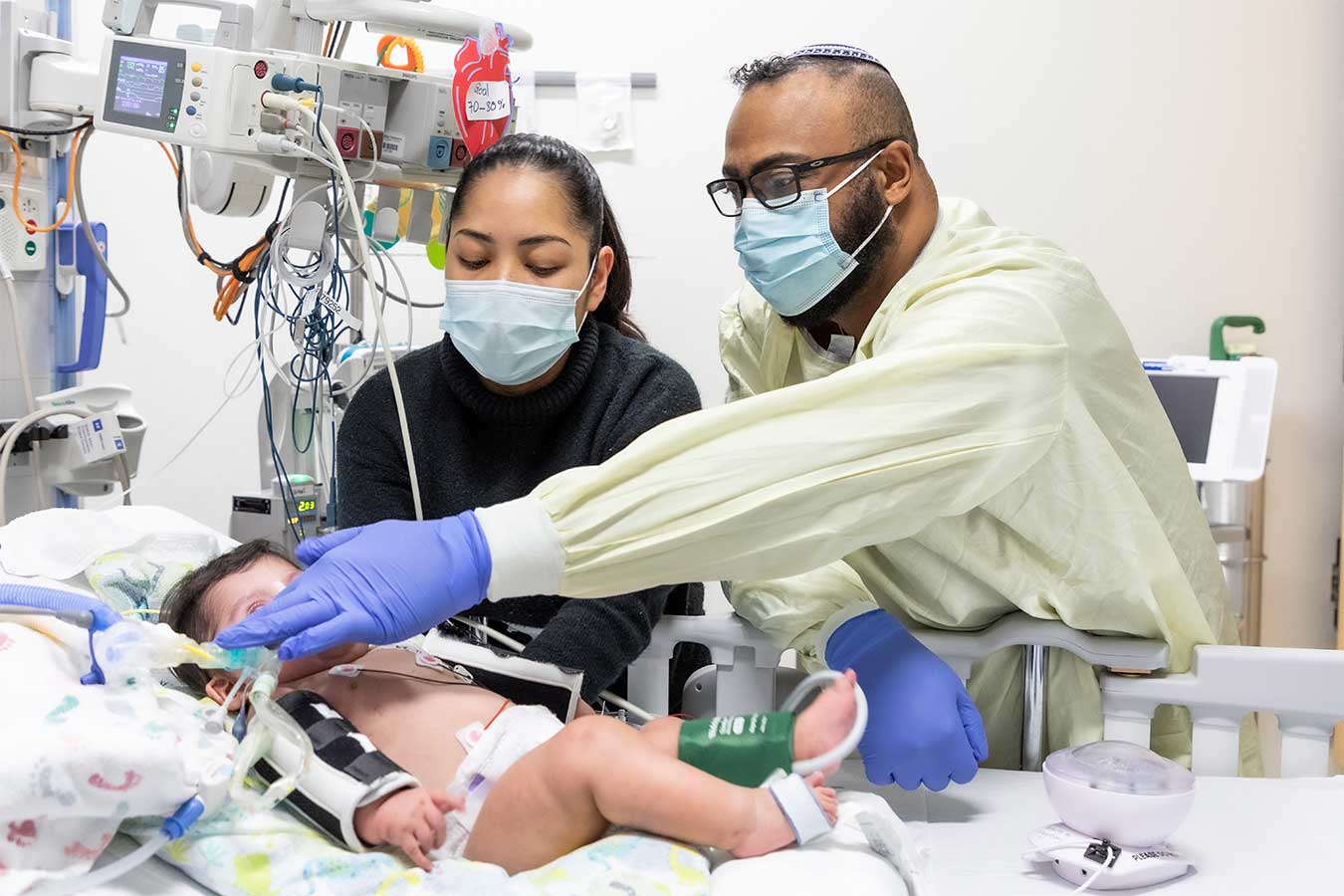 A nurse adjusts the tubing of a toddler in a hospital bed
