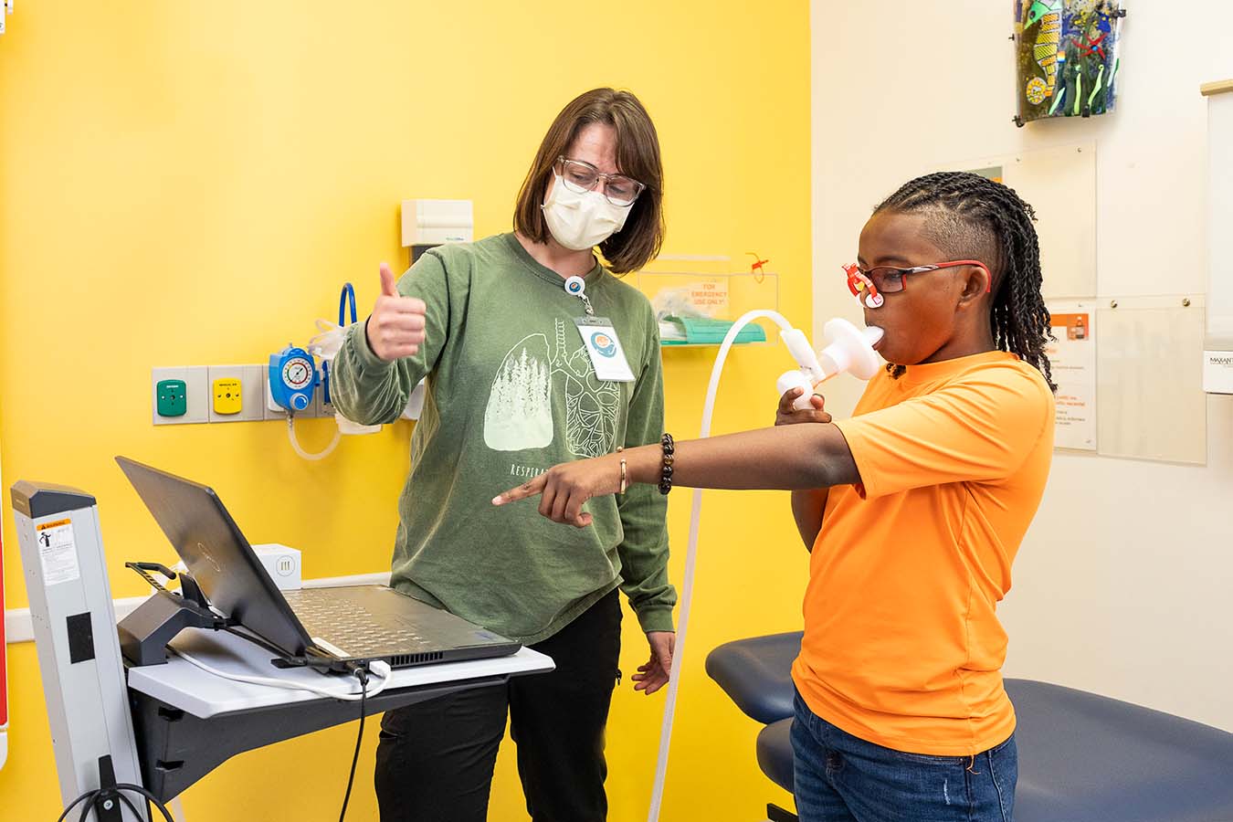 A Seattle Children's provider helps a patient, who is blowing into a tube.