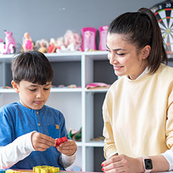 A woman helps a boy with a task at a table